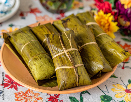 Venezuelan hallacas wrapped in banana leaves arranged on a festive table setting