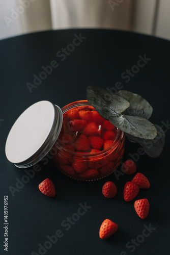 Tender aroma candle decorated with berries on a black table. Cosy modern home atmosphere.