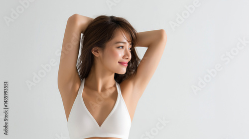 腕を後ろに組んでワキ（脇）を見せる笑顔の女性、白い水着と明るい背景（美容・エステ・脱毛・コスメ・健康）