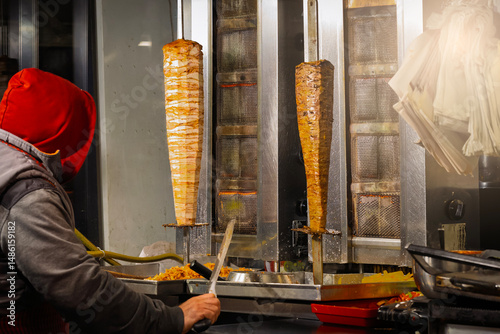 Street vendor slicing döner kebab at a fast food stand in Istanbul, Turkey. Grilled meat on rotating skewers. Photo taken on March 6, 2025.