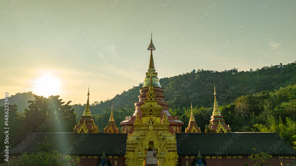 Obraz premium aerial view of the golden gate with intricate golden architecture at Phra Yai Wat Phra That Doi Phra Chan (Daibutsu) temple..A stunning view of a traditional temple surrounded by lush greenery