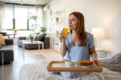 Bild auf Leinwand Woman enjoying breakfast in bed with orange juice and waffles