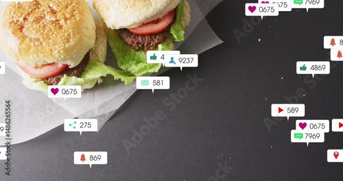 Two sesame burger sliders resting on parchment with social media icons floating as flat design