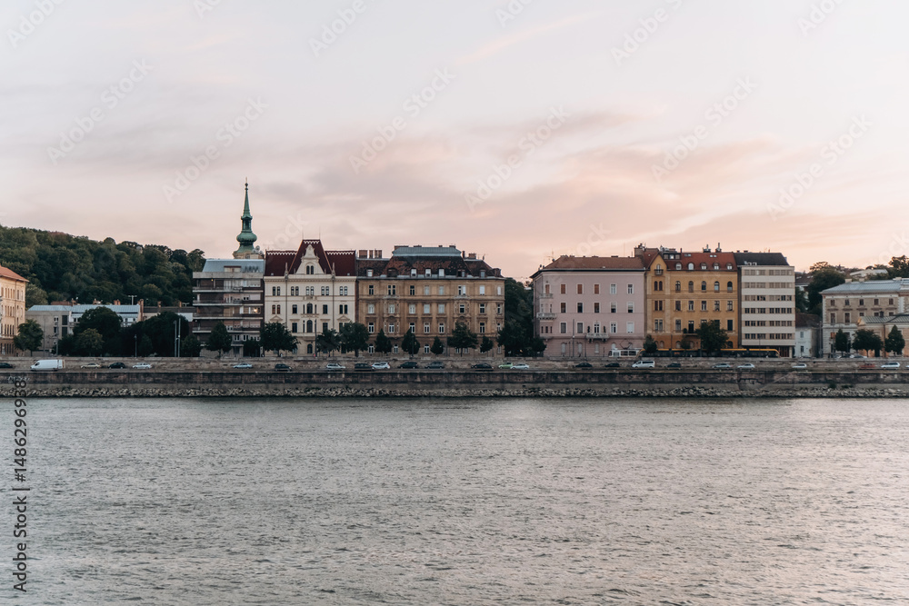 Obraz premium Charming Riverside Buildings at Sunset Captured Beautifully Against a Colorful Sky