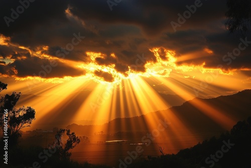Sunset over mountains with rays of light illuminating the sky and landscape during early evening hours
