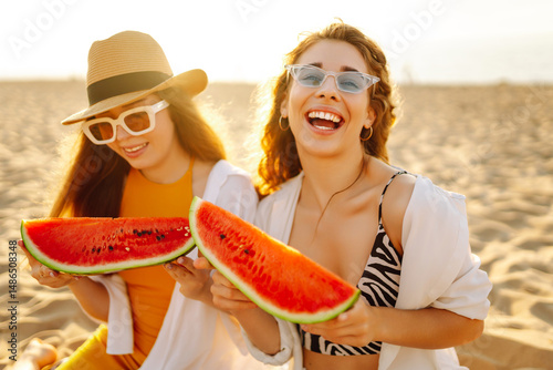 Wallpaper Mural Two young female friends eating watermelon on a picnic near the sea. Beautiful women having fun and enjoying the seascape at sunset. Concept of friendship, time together. Torontodigital.ca