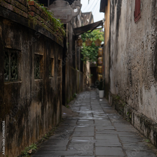 A very narrow and curved street with shabby yellow walls. There are no people on the street. There are damp and humid, quiet and peaceful.