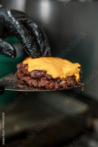 Close-up of Chef Holding Juicy Smash Burger Patty with Melted Cheddar Cheese