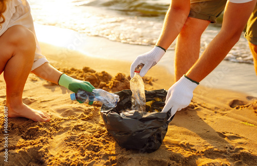 Wallpaper Mural Young friends actively participate in beach cleanup. Cheerful volunteers collect plastic waste and trash along the coastline at sunset. The concept of ecology, ecology and recreation. Torontodigital.ca