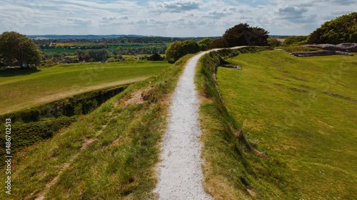 Weathered earthwork banks and ruined foundation stones punctuate the windswept summit of Old Sarum, Salisbury, Wiltshire, England, UK