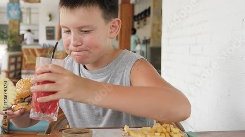 Overweight child eating fast food and drinking soda in cozy cafe environment Soda consumed frequently reflects growing dependency Soda symbolizes root of childhood obesity poor health emotional eating
