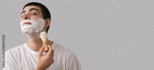 Young man shaving against g...