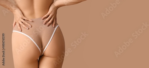 Young woman in panties on beige background with space for text, back view
