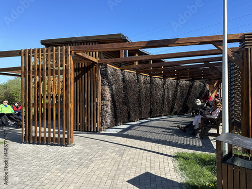 Modern architectural structure featuring wooden slats and natural materials, providing shaded seating area for relaxation and social interaction