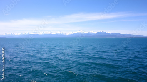 large open water surface with far snowcapped mountain range on the horizon at sunny day.