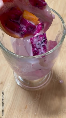 A refreshing fruit cocktail served in a clear glass with colorful fruits and ice.