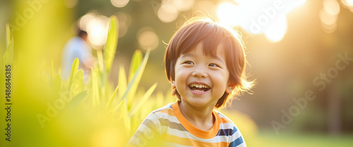 Bright Sunny Portrait of a Joyful Asian Boy Playing Outdoors: Capturing Natural Light and Carefree Happiness in Stock Photography with Empty Space for Text