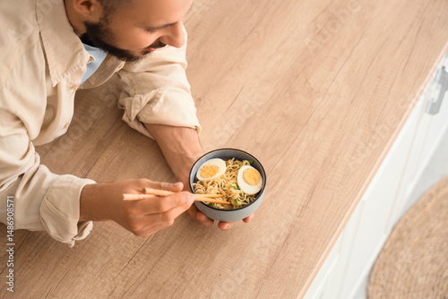 Young man eating tasty rame...