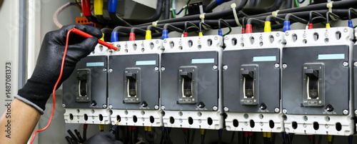 Electrical technician hand checking electricity circuit breaker main power on switchboard cabinet for service maintenance and electric cable wiring check for safety concepts.