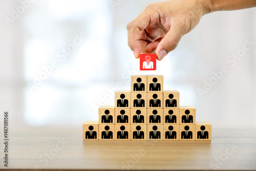 Hand chooses cube wooden block stack pyramid with person icons for HR human resources or personal leader training skill or leadership and business team player challenge and organization management