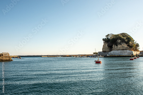 Peaceful winter morning panorama of Hirakata Fishing Port in Kitaibaraki, Ibaraki Prefecture, Japan – calm blue Pacific waters, small fishing boats and red marker buoys beneath a clear sky

 photo