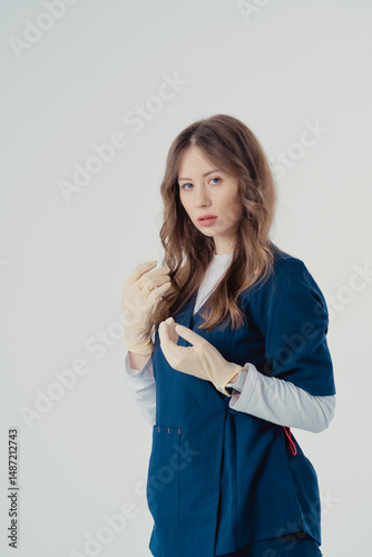 A beautiful young nurse put her hands in beige gloves