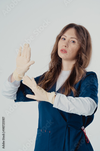 A beautiful young nurse put her hands in beige gloves
