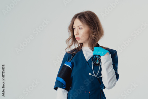 Happy female doctor with stethoscope on white background. Polite smiling young woman therapist in blue uniform with stethoscope on her neck 