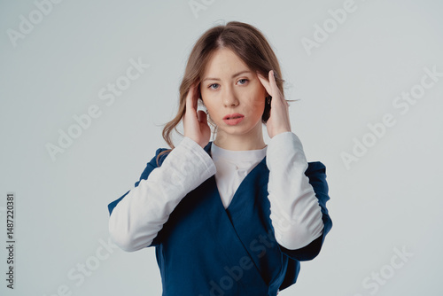Portrait of a cardiologist girl in a blue uniform with her hands near her face on a white background, with copy space to the side.