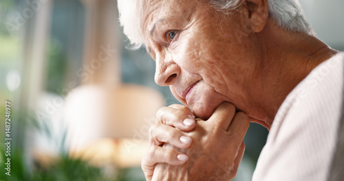 Senior woman, unhappy and thinking in home for loneliness, remember memory or past trauma. Thoughts, sad and elderly person with regret in lounge with depression, dementia and alzheimers in profile