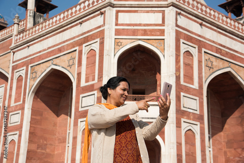 Indian woman taking selfie with smartphone in front of Humayun's Tomb