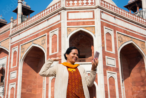 Indian woman taking selfie with smartphone in front of Humayun's Tomb