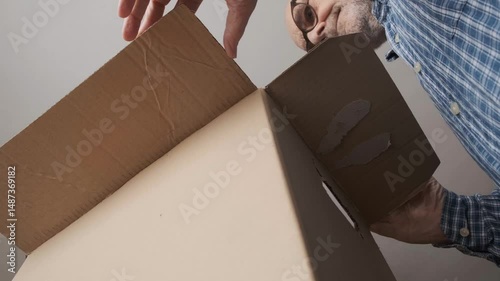 Man Opening Large Cardboard Box from Unique Low Angle Perspective