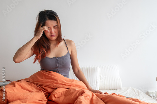 Εκτύπωση καμβά Asian woman rubbing eyes while sitting up in white orange bed