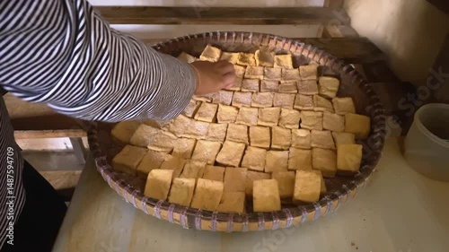 Hands arranging tofu on trays in a traditional tofu factory