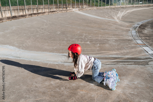 Girl learning to roller skate in outdoor skate park photo