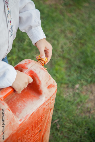 Young boy screwing lid on petrol can