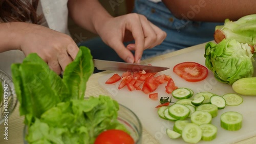Close-up hand of woman roughly chopping tomato in home kitchen.