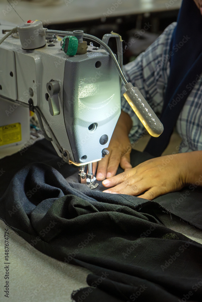 Obraz premium hand with sewing machine in clothing factory, textile and industry concept.