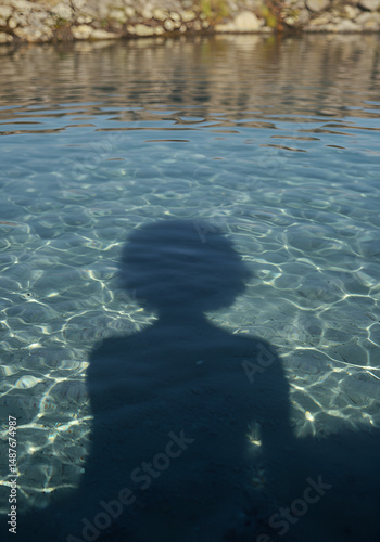 Shadow of a person in a crystal-clear pool