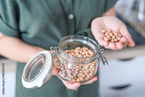 A close-up of chickpeas in a woman s hands this product helps lower cholesterol and maintains healthy skin. Concept: culinary blogs, dietetics, fitness.