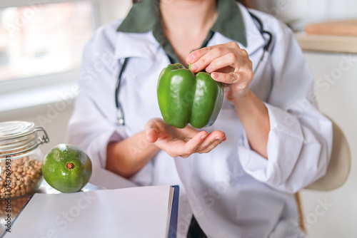 Nutritionist showing fresh green pepper regular consumption of vegetables enriches the body with vitamins and minerals concept: health, wellness center.