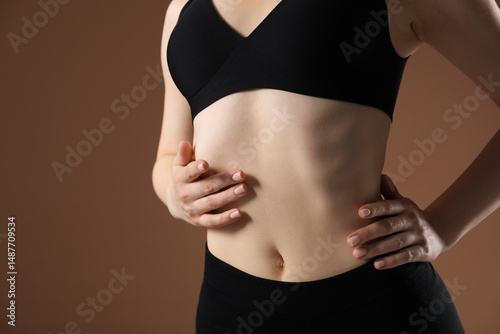 Attractive woman against brown background, closeup on belly