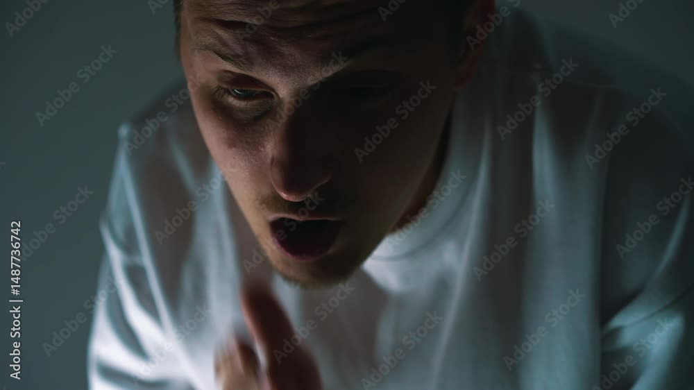 A guy has shortness of breath after active physical activity.
The man is trying to regain his breath.
It is difficult for a person to breathe in a dark room