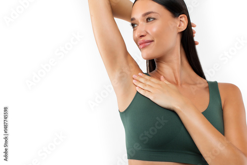 Hair removal concept. Young lady demonstrating her armpit with smooth skin, posing in green underwear over white background and looking aside at copy space