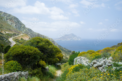 Scenic mountain road winding along the coast with view of a remote island and the Mediterranean Sea in spring