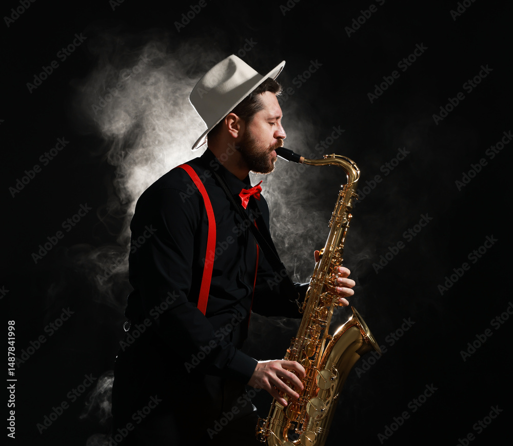 Naklejka premium Professional musician playing saxophone on black background with smoke. Space for text