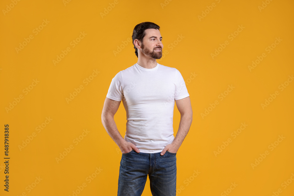 Fototapeta premium Man wearing blank white t-shirt on orange background. Mockup for design