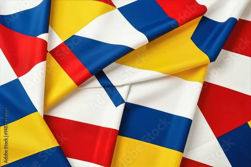 A vibrant abstract flag with geometric patterns of red, yellow, blue, and white drapes against a black backdrop.