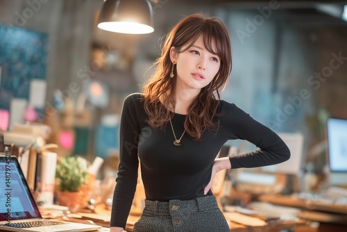働く女性がオフィスで立ち上がり腰痛で悩むビジネスシーン